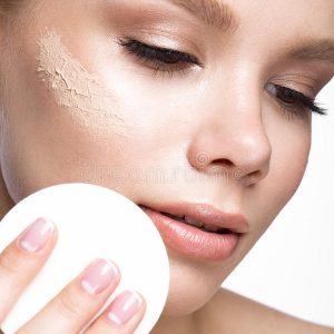 chica-joven-hermosa-con-la-esponja-para-el-maquillaje-del-uso-y-la-manicura-francesa-cara-de-la-belleza-78065341